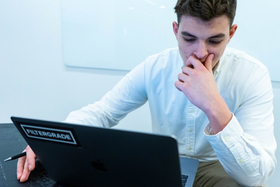 A student thinking hard in front of a laptop
