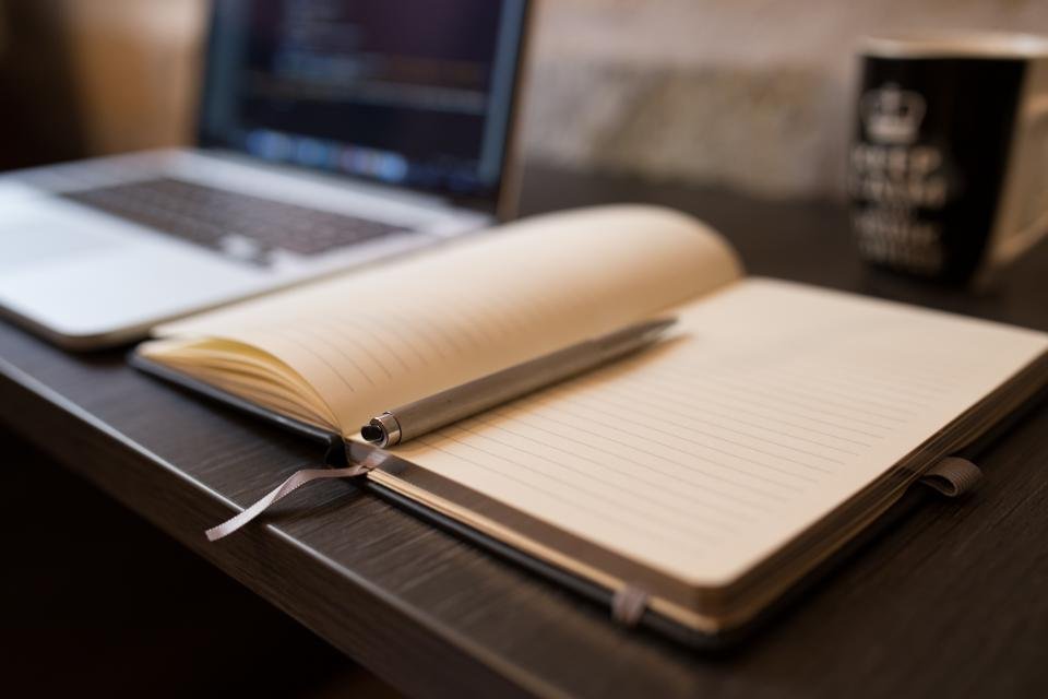An open notebook beside a laptop